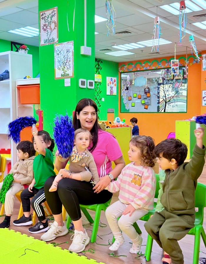 An educator singing with children during circle time in a bright Little Feet classroom