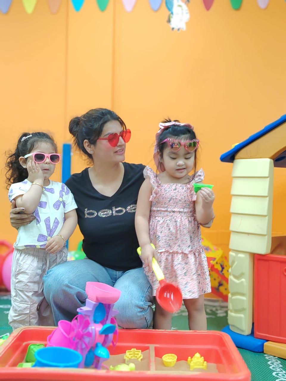 An educator and two children exploring a sand tray at Little Feet