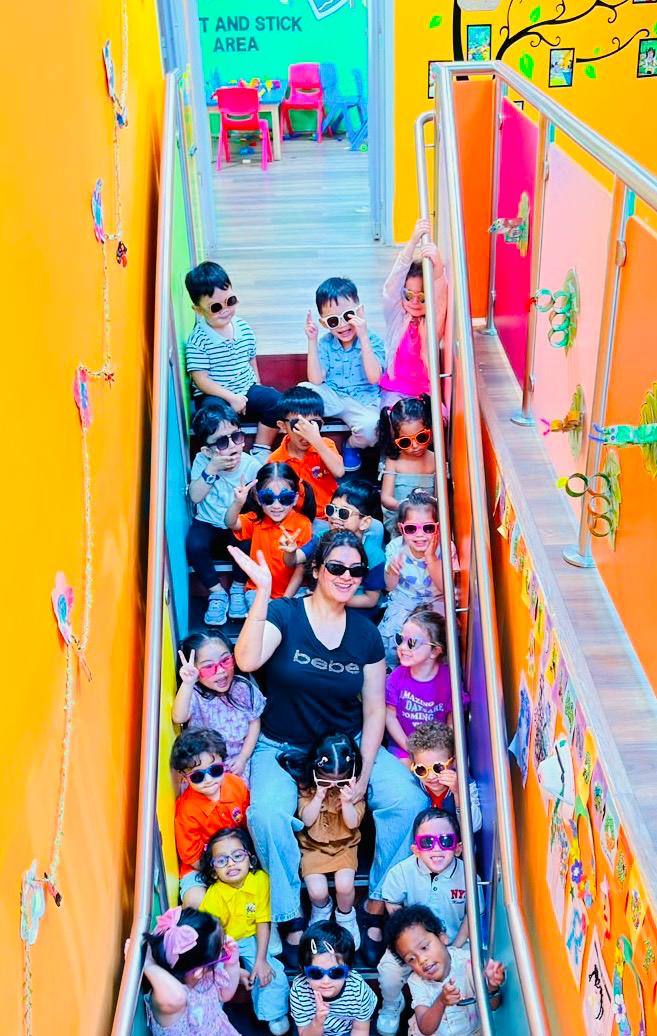The whole class and their educator in colourful sunglasses on the nursery stairs
