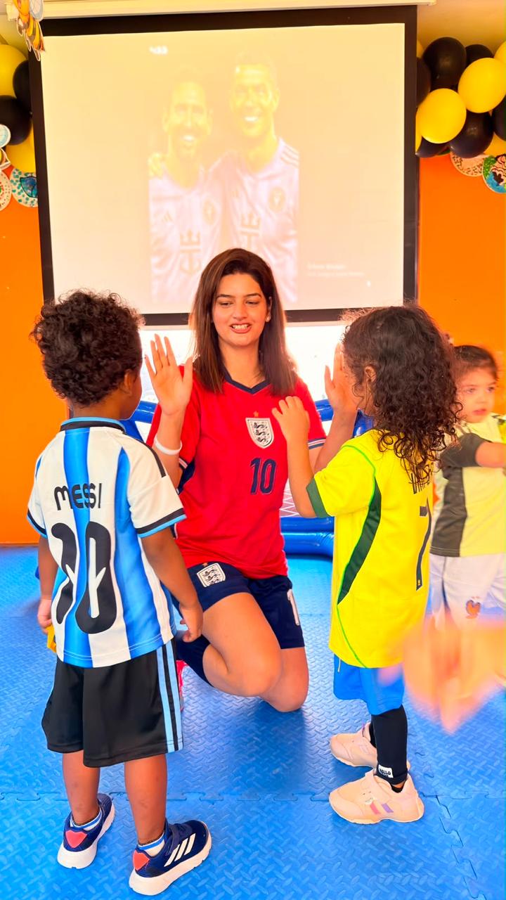 Children in football kits high-fiving their educator on World Cup Day